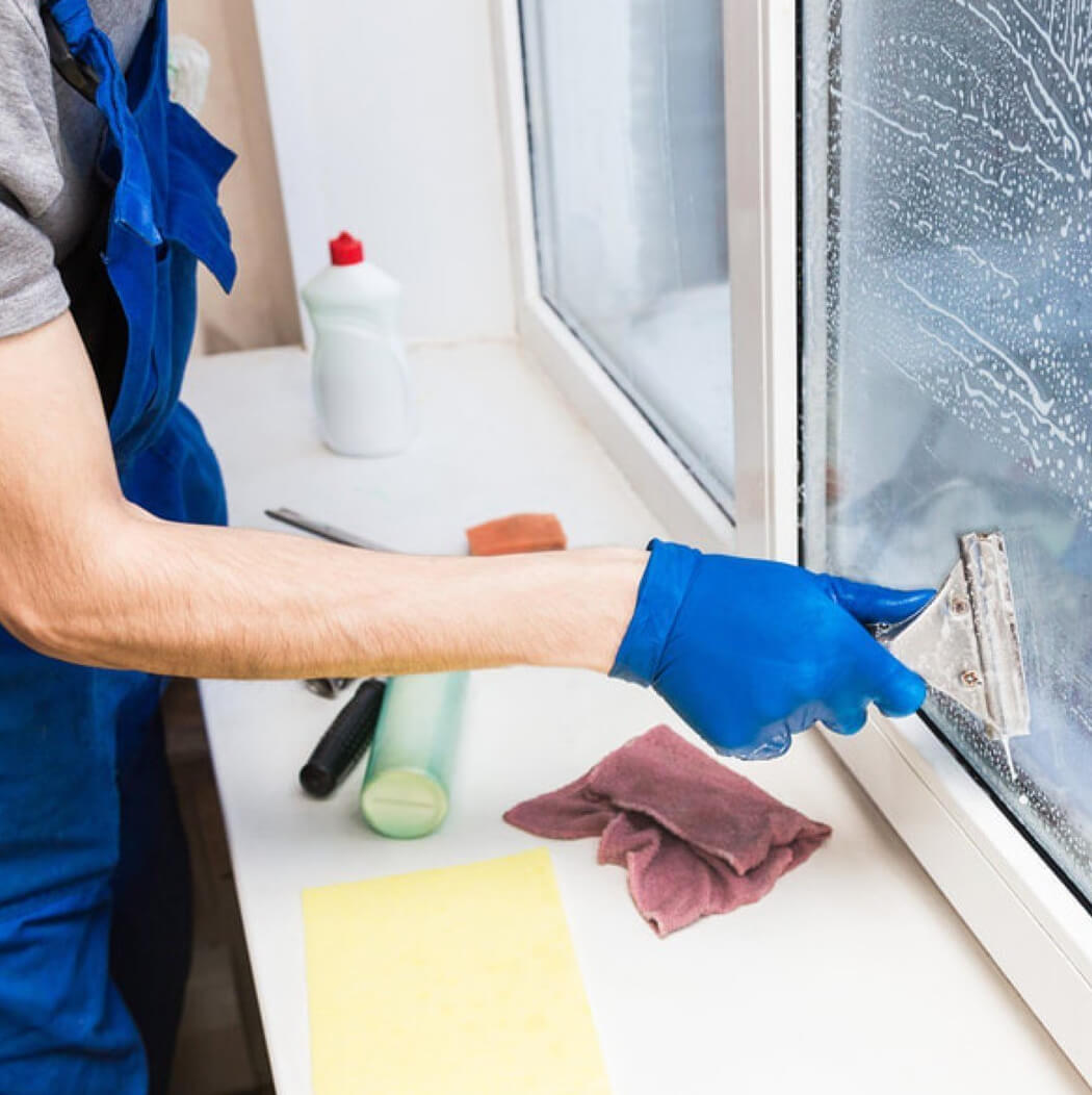A person wearing blue gloves cleaning a window
